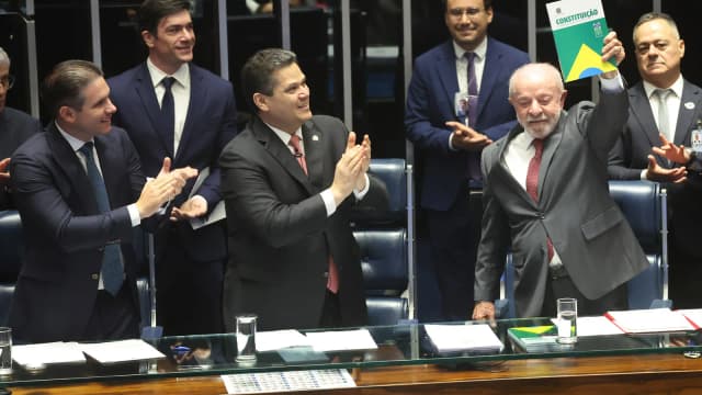 Luiz Inácio Lula da Silva sorri e ergue um exemplar da Constituição em plenário do Congresso