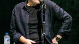 Phil Collins sentado ao microfone durante apresentação no Royal Albert Hall, em Londres