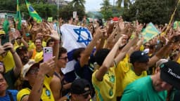 Apoiadores em ato bolsonarista erguem bandeiras do Brasil e cartazes em manifestação