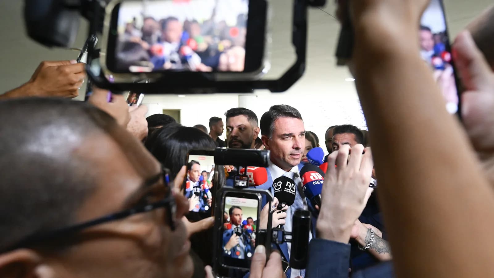 Flávio Bolsonaro fala a jornalistas cercado de microfones de emissoras de TV