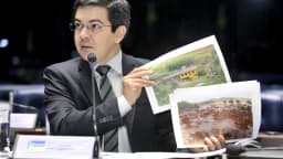 Randolfe Rodrigues fala ao microfone segurando imagens de satélite durante sessão no Senado