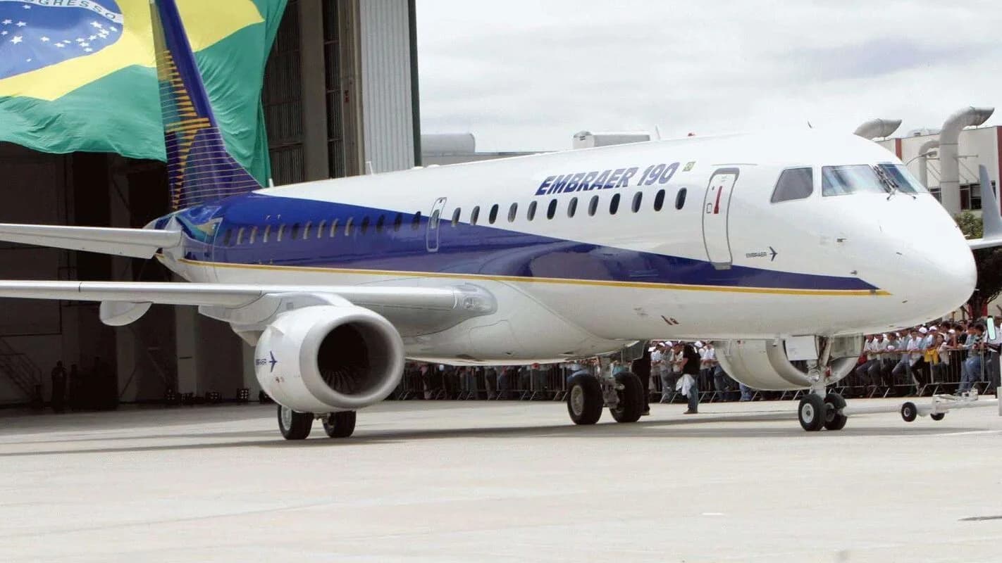 Jato da Embraer estacionado em pátio, com bandeira do Brasil ao fundo (foto de arquivo)