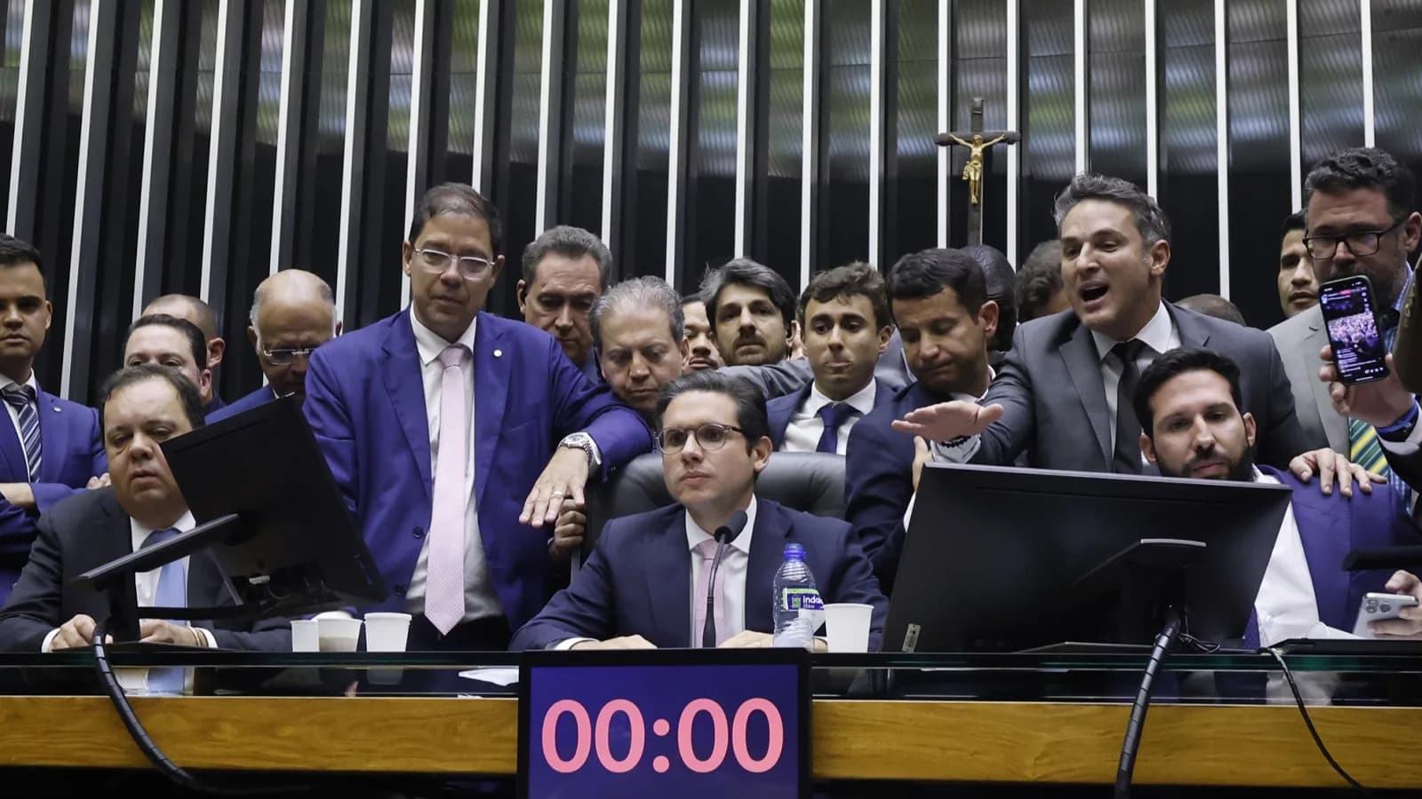 Deputado Hugo Motta cercado por parlamentares na mesa diretora da Câmara dos Deputados