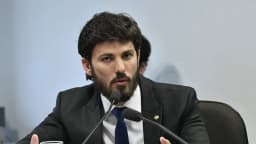 Marcelo Aro fala ao microfone em audiência pública, de terno escuro e barba