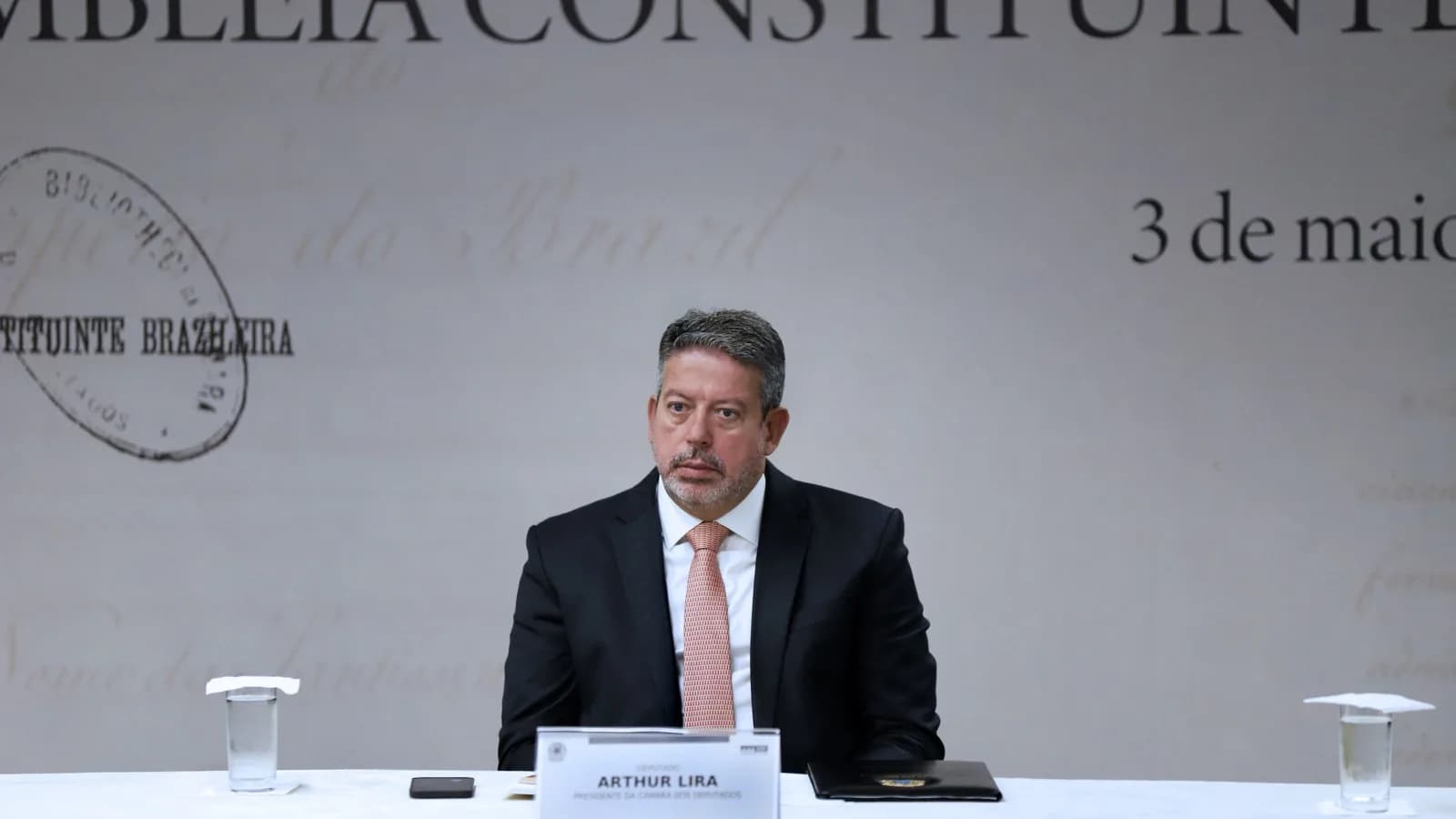Arthur Lira, presidente da Câmara dos Deputados, sentado à mesa em evento institucional em Brasília