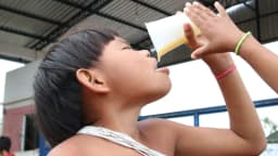 Criança bebendo líquido em copo, ilustrando hábitos alimentares