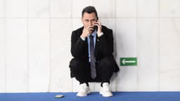 Foto de arquivo do senador Cleitinho, de terno preto e gravata, agachado ao lado de uma parede de mármore enquanto fala ao celular no Senado Federal