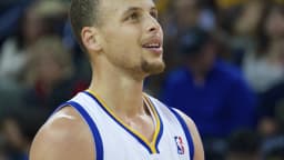 Stephen Curry em close, olhando para cima, com o uniforme do Golden State Warriors
