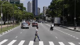 Avenida Faria Lima, no centro financeiro de São Paulo, com pedestre atravessando a rua e prédios comerciais ao fundo