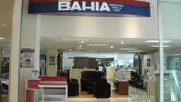 Fachada de loja da Casas Bahia em shopping, com letreiro da marca e vitrine de móveis