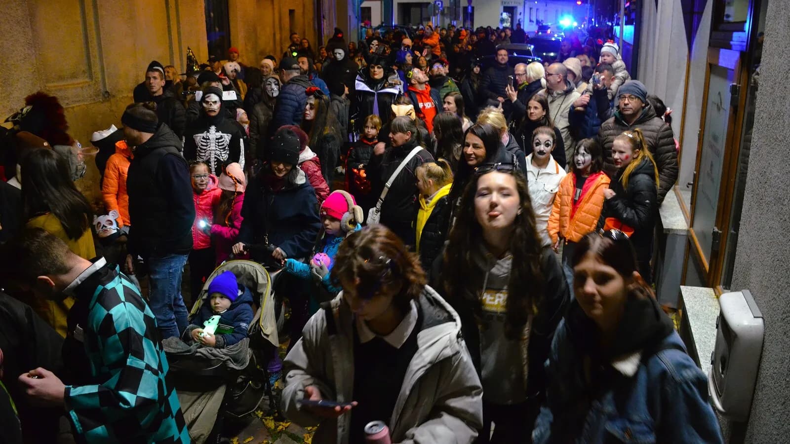 Multidão fantasiada de caveiras e zumbis em desfile de rua de Halloween à noite