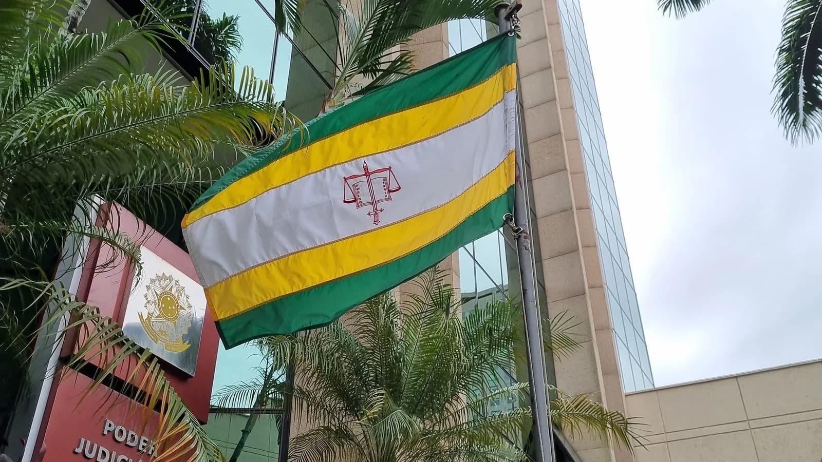 Bandeira com o símbolo da balança da Justiça em fachada de tribunal