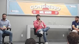Renan Santos discursando com microfone em evento do MBL, sentado ao lado de outros participantes de painel