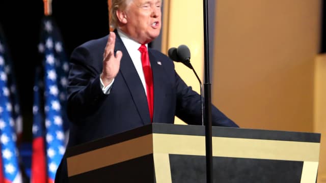 Donald Trump discursa em púlpito com bandeiras dos Estados Unidos ao fundo, foto de arquivo
