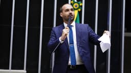 Eduardo Bolsonaro discursa ao microfone segurando um papel durante sessão na Câmara dos Deputados