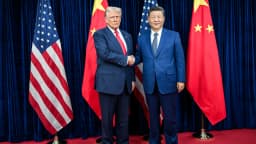 Donald Trump e Xi Jinping apertam as mãos diante das bandeiras dos Estados Unidos e da China