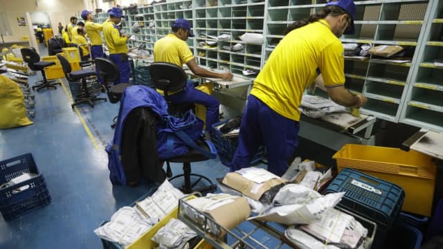 Carteiros dos Correios trabalham triando encomendas em centro de distribuição durante a greve da categoria