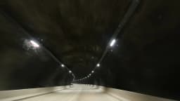 Túnel da rodovia BR-381 visto de dentro de um veículo em movimento, com luzes no teto