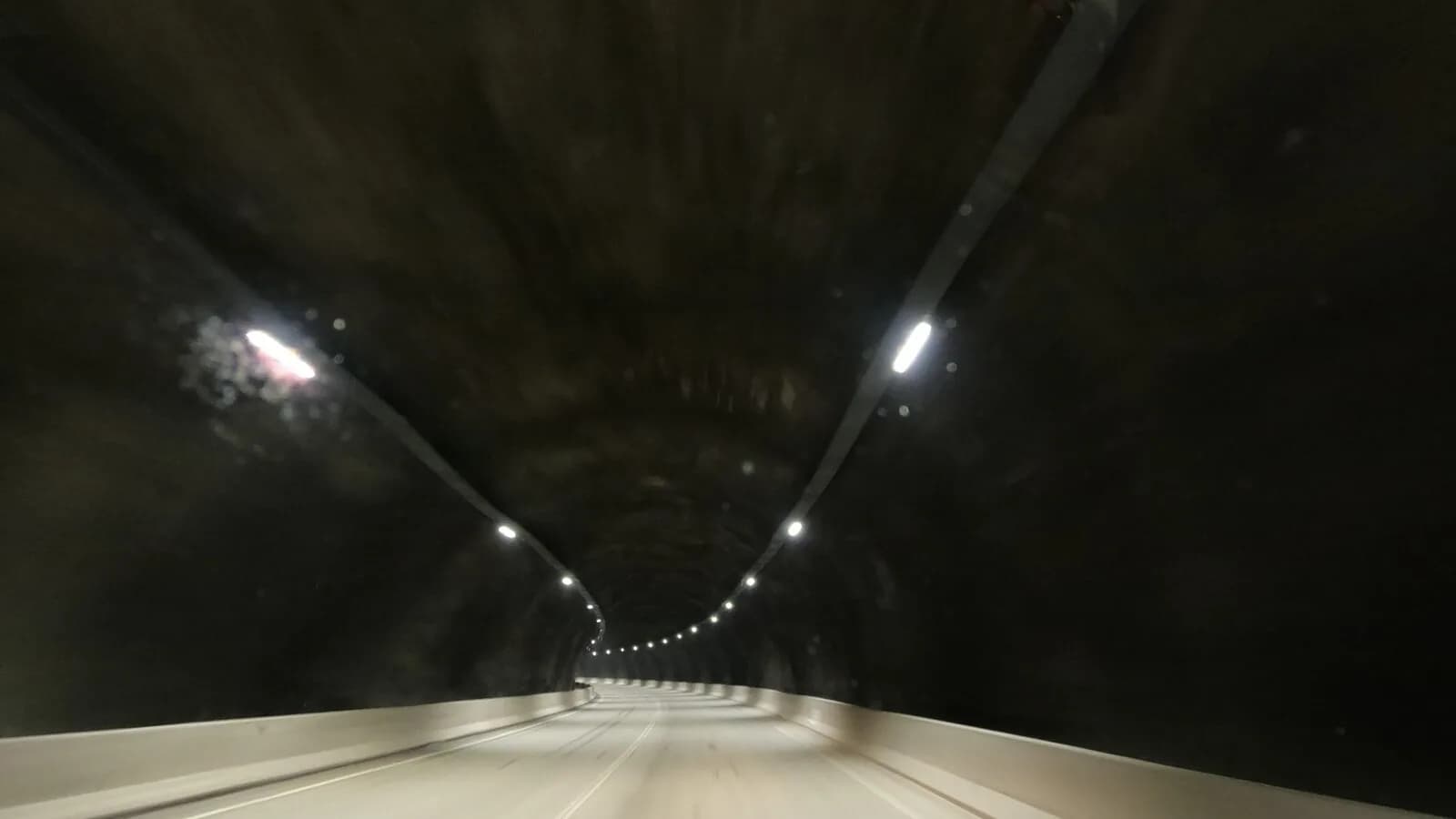 Túnel da rodovia BR-381 visto de dentro de um veículo em movimento, com luzes no teto