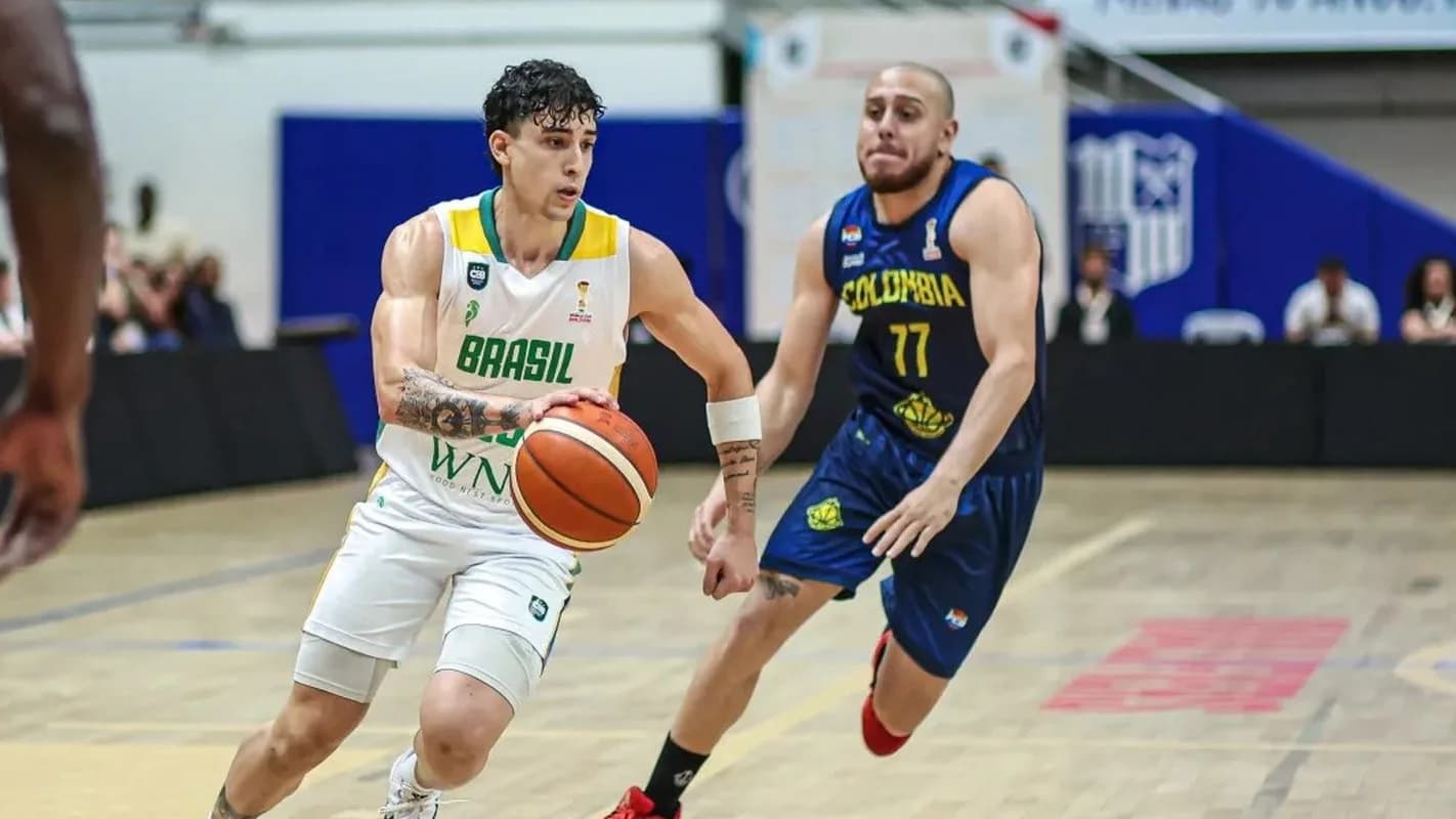 Jogador da seleção brasileira de basquete conduz a bola diante de um marcador da Colômbia