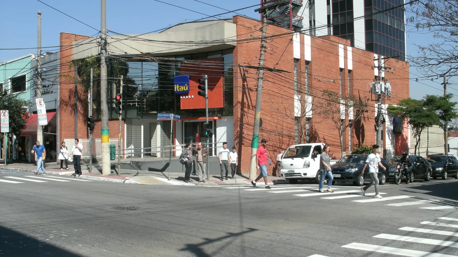 Agência do Itaú em esquina de São Paulo, com pedestres atravessando a rua