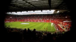 Gramado de Old Trafford durante partida, com torcida nas arquibancadas