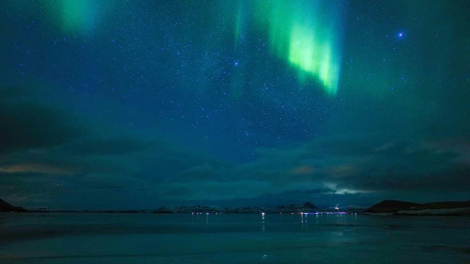 Aurora boreal verde iluminando o céu noturno sobre o lago Mývatn, na Islândia