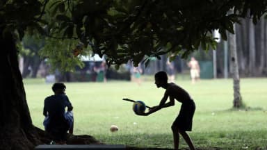 Pessoas em um parque à sombra de árvores em dia de calor, foto de arquivo