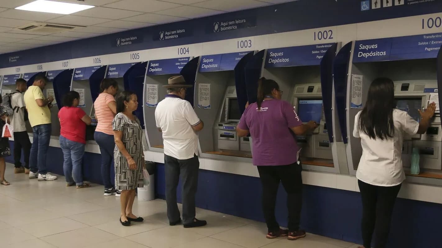 Pessoas em fila usando caixas eletrônicos de banco