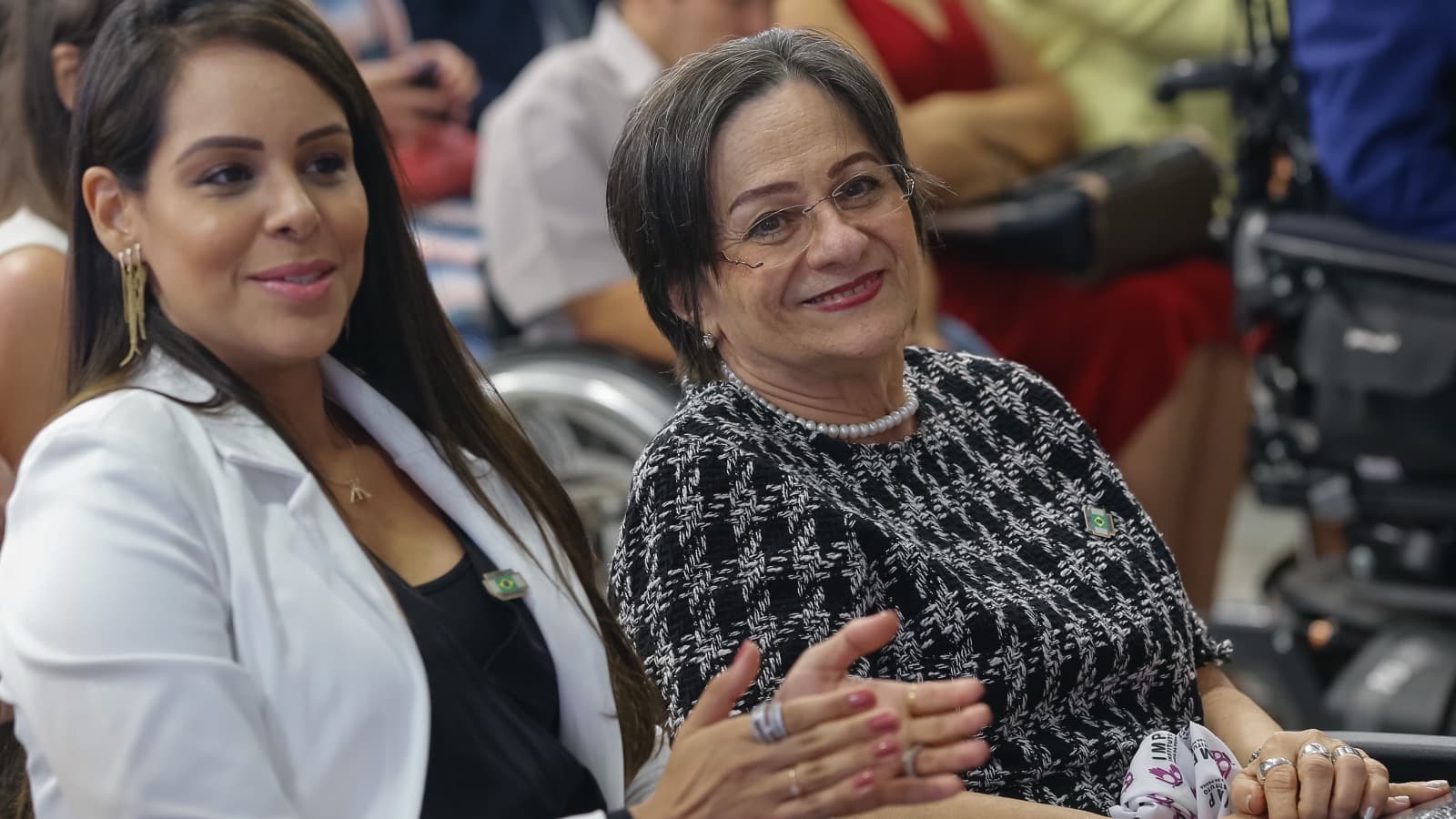 Maria da Penha Maia Fernandes, que dá nome à Lei Maria da Penha, sentada na plateia de um evento ao lado de outra mulher, em imagem de arquivo de novembro de 2018