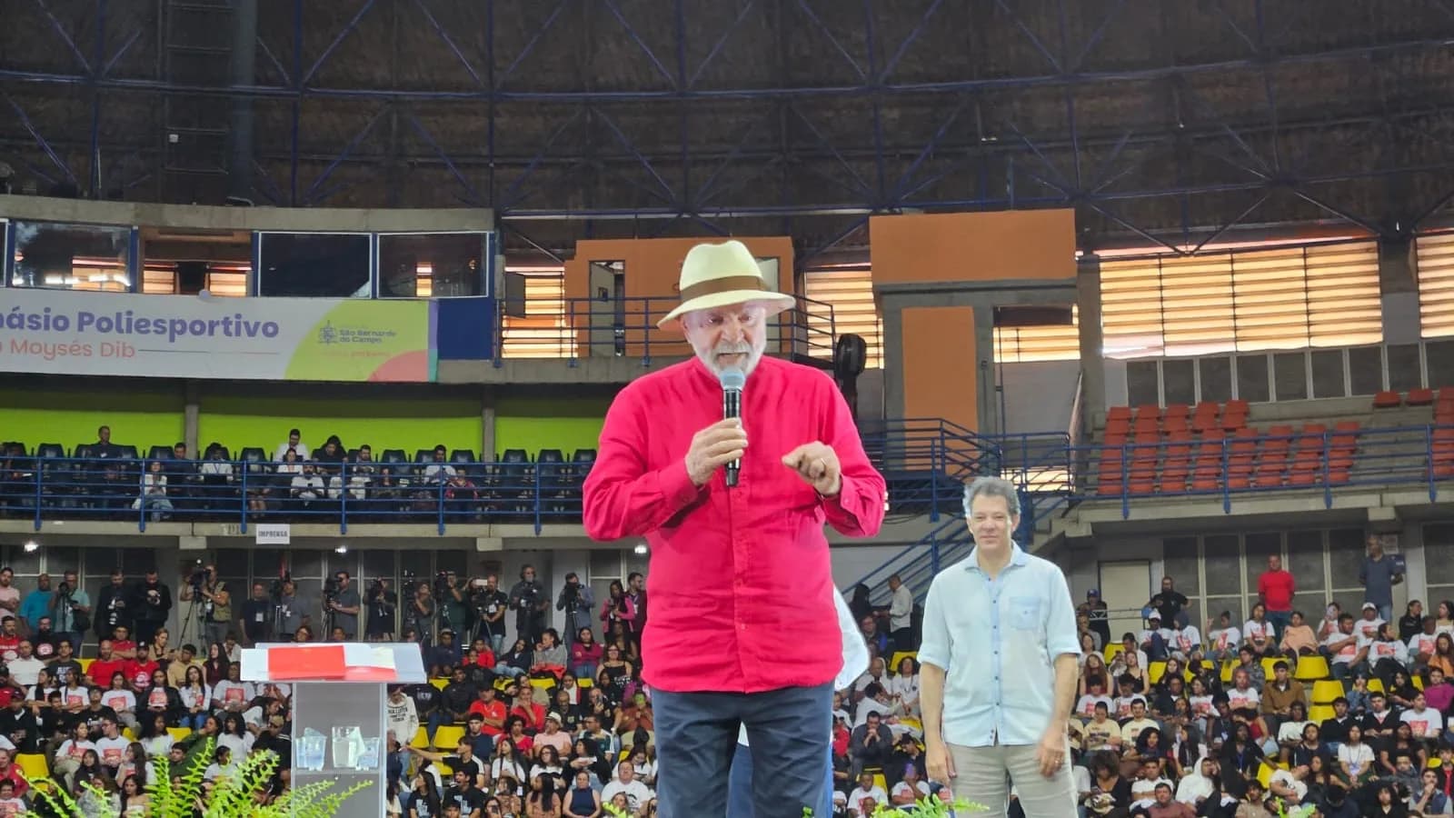 Lula discursa com microfone durante evento de campanha em ginásio lotado em São Bernardo do Campo