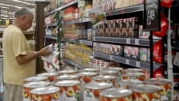 Consumidor observa rótulo de produto industrializado em prateleira de supermercado
