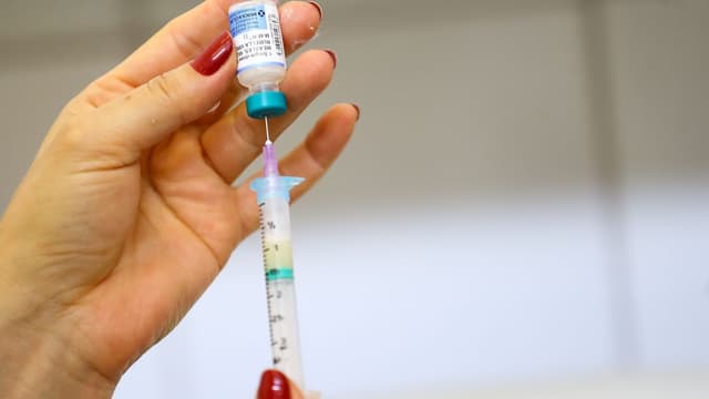 Profissional de saúde prepara dose de vacina tríplice viral em seringa