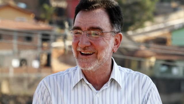 Patrus Ananias sorri em foto ao ar livre com Minas Gerais ao fundo