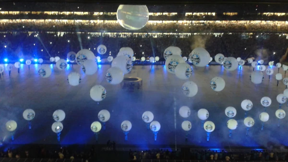 Interior da Arena do Grêmio em dia de jogo, com balões brancos no gramado (imagem de arquivo)