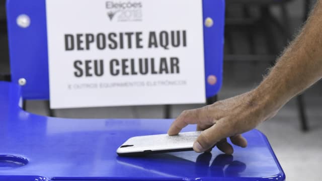 Cabine de votação com aviso para depositar celular e outros equipamentos eletrônicos antes de votar (foto de arquivo de eleição anterior)