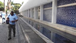 Fachada do Palácio das Artes, em Belo Horizonte, com pedestre caminhando junto ao espelho d'água