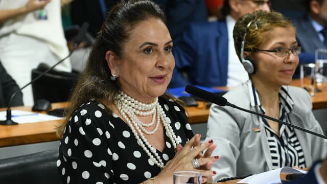 Kátia Abreu fala ao microfone durante reunião, ao lado de outra parlamentar