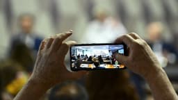 Mãos seguram um celular para fotografar documento, foto de arquivo ilustrativa