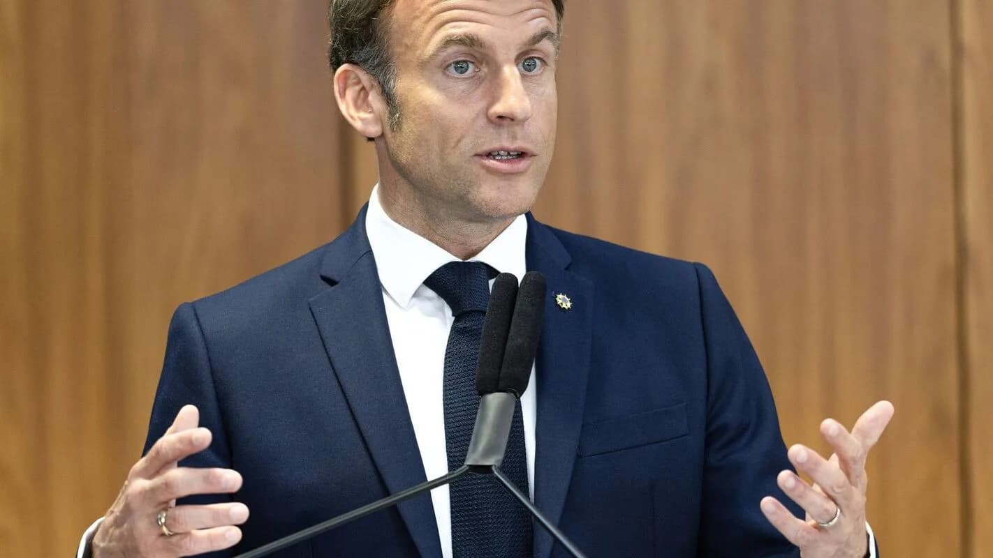 Presidente francês Emmanuel Macron fala gesticulando diante de microfones