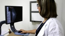 Profissional de saúde analisa imagem de mamografia em consultório
