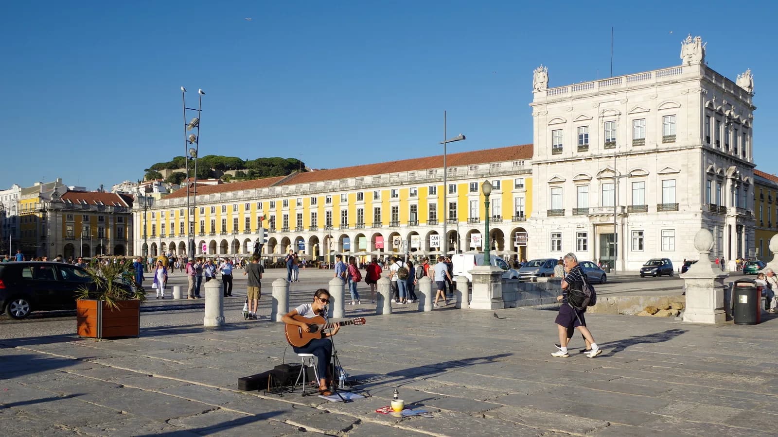 Praça do Comércio, em Lisboa, com turistas e músico de rua