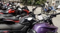 Entregadores de aplicativo em motocicletas no trânsito de uma cidade brasileira
