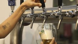 Mão servindo chope em copo de vidro em torneira de bar