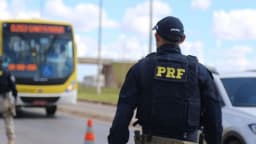 Agente da PRF fiscalizando ônibus em rodovia durante operação de trânsito