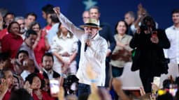 Lula discursa com o punho erguido durante a convenção do PT em São Paulo, cercado por apoiadores
