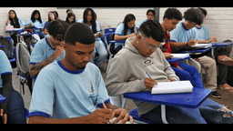 Estudantes de escola pública escrevem em cadernos durante aula, foto de contexto sobre estudo e desempenho escolar