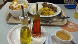 Bandeja de almoço em restaurante self-service com prato de arroz, carne e legumes, tigela de salada, galheteiro e xícara de café, em foto de arquivo