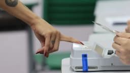Mão de eleitor digita na tela de uma urna eletrônica durante votação