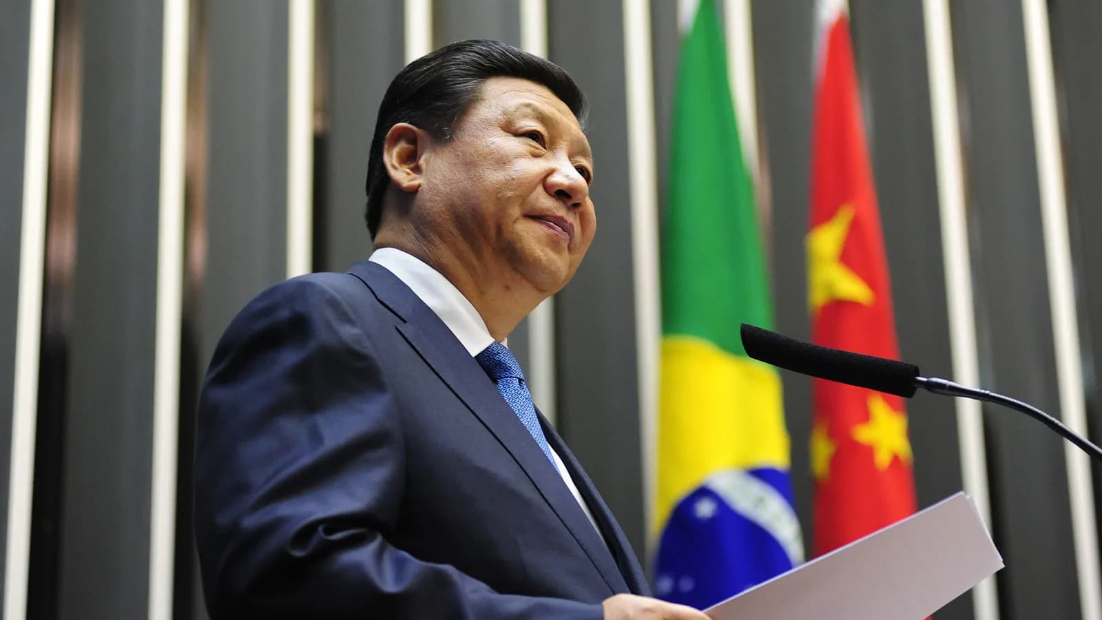 Xi Jinping discursa em evento com bandeiras do Brasil e da China ao fundo